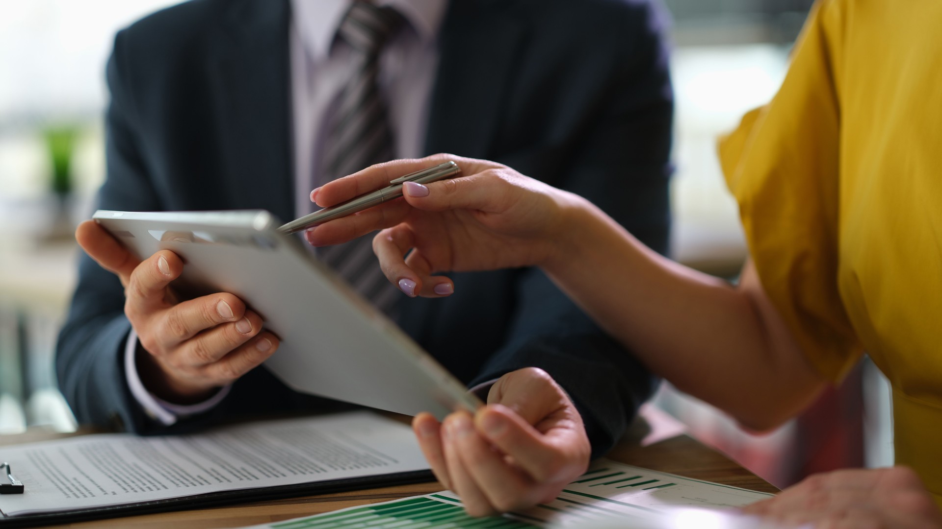 Two business partners are discussing information on tablet computer